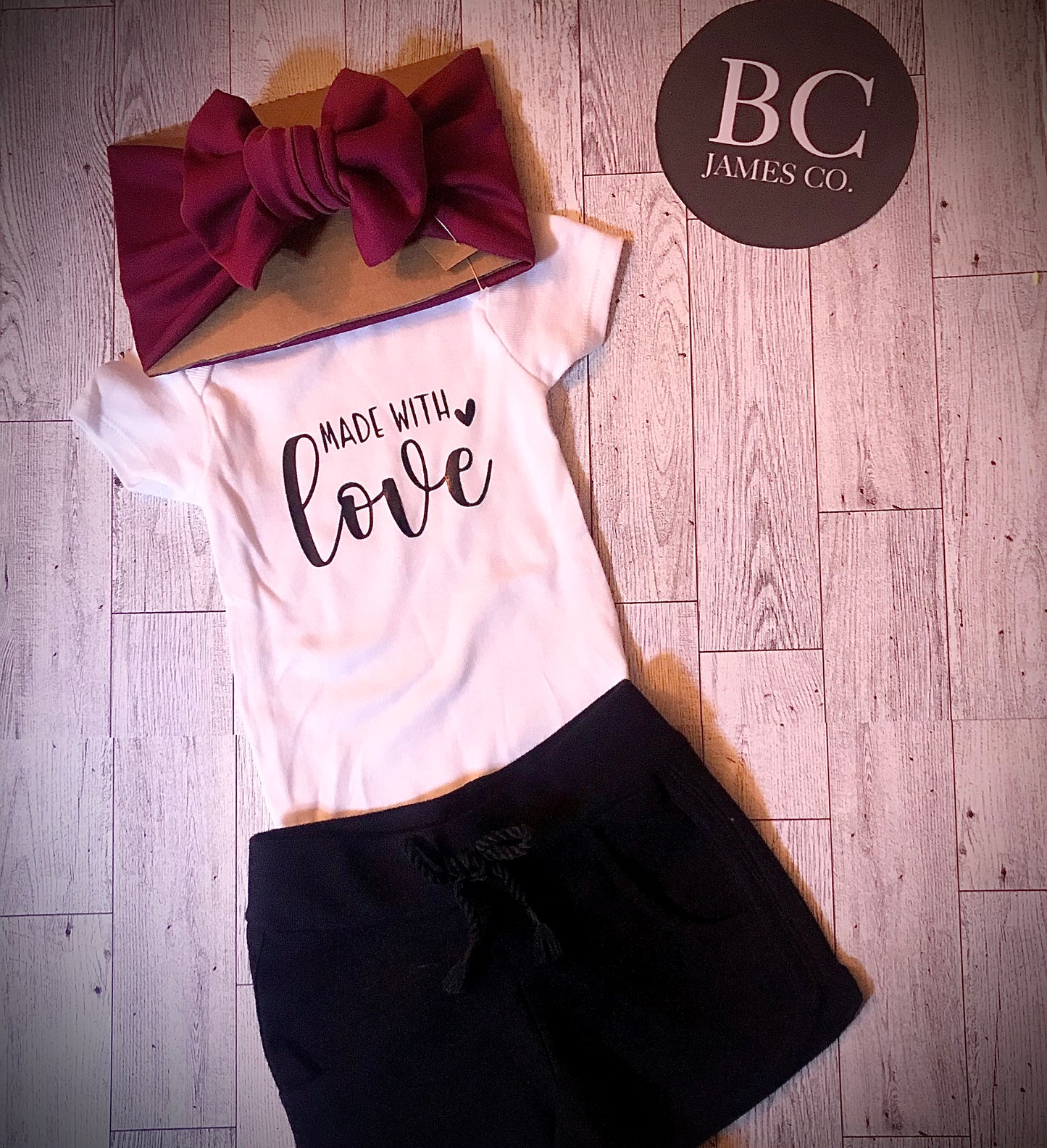 “Made with love” onesie with burgundy head wrap bow style headband and little black shorts, B.C JAMES CO.