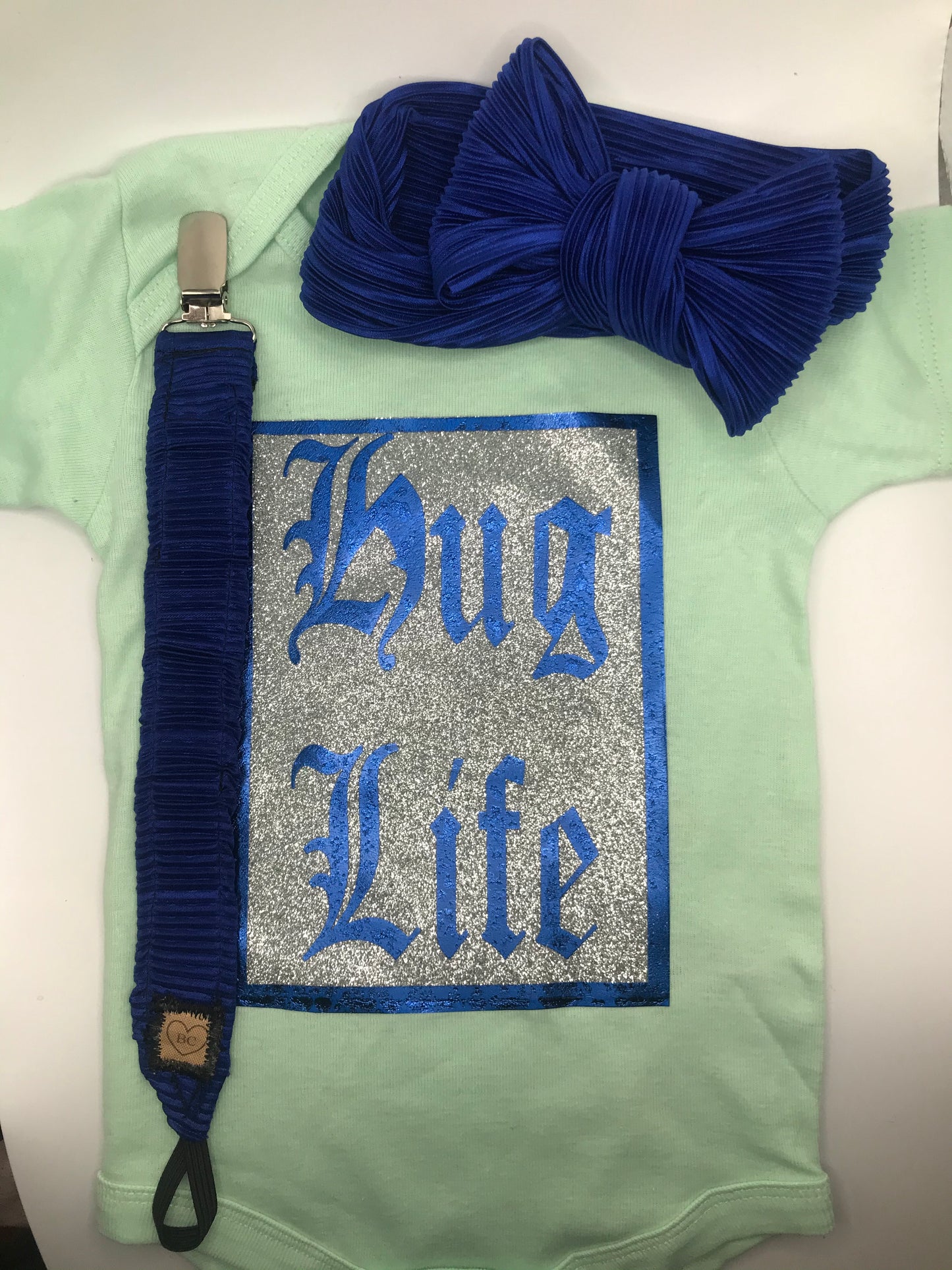 Teal “HUG LIFE” onesie with royal blue binki clip and bow headband